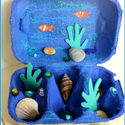 Blue ocean diorama made of egg cartons with sea shells, sea grasses and gems