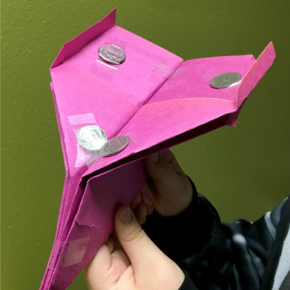 folded paper plane carrying coins as paper plane crafts for kids