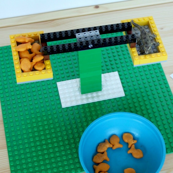 Lego Balance Scale Activity for Kids with Goldfish Biscuits and Aligator as weights.