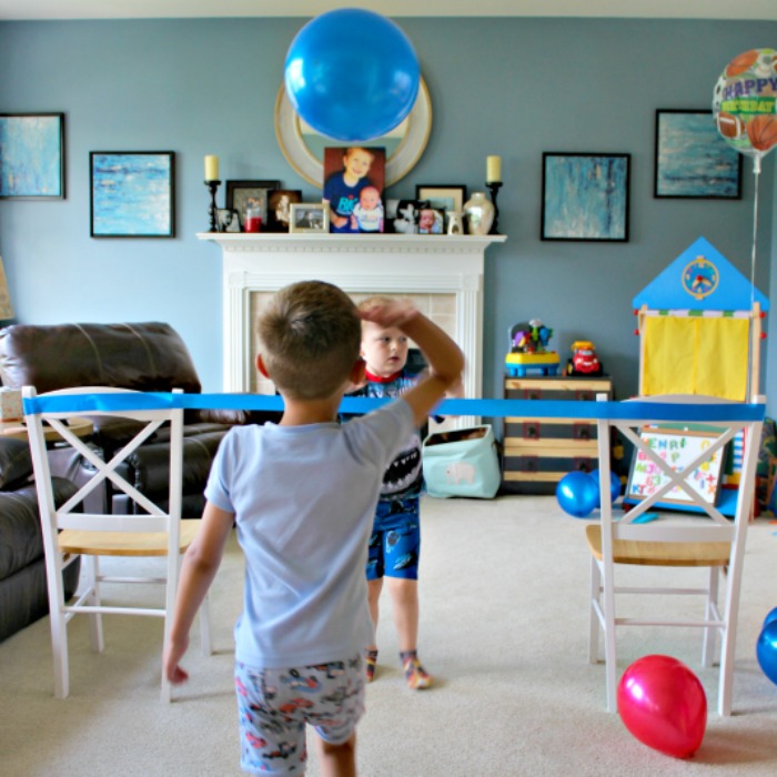 2 boys playing indoor volleyball for a slumber party. Made of a pair of chairs,  ribbons for net, and balloons as the ball