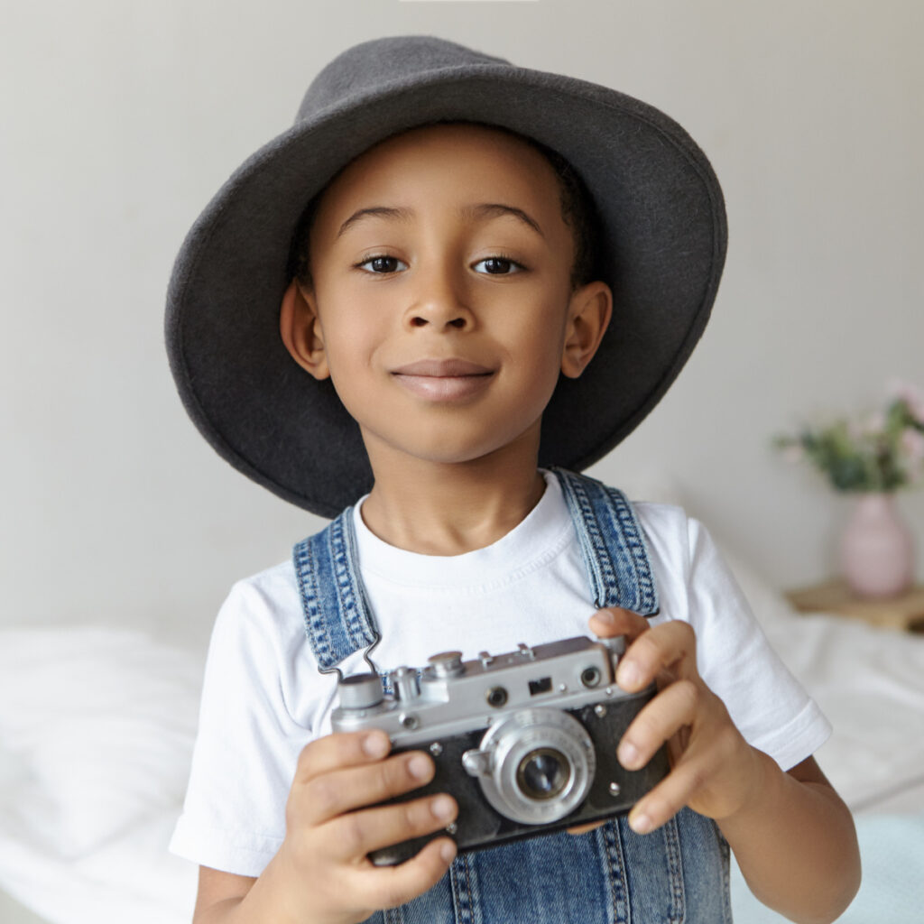 child with camera in bedroom wearing hat for scavenger hunt